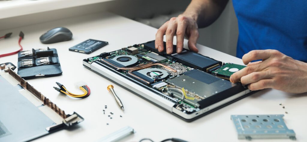 computer repairman installing new hard disk drive in laptop